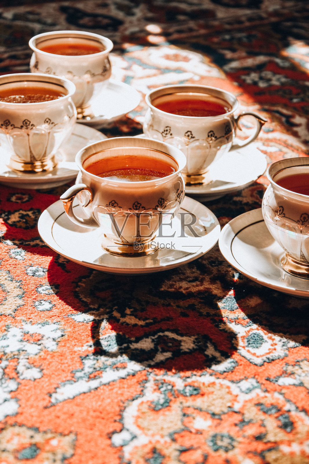 老式苏联瓷杯和茶碟放在土耳其地毯上，传统茶道，阳光照片摄影图片