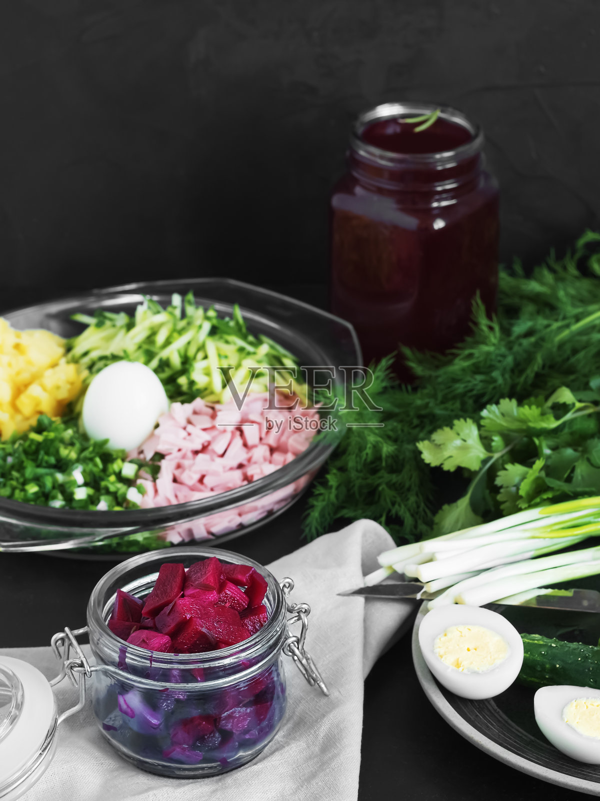 制作冷罗宋汤的配料。盛在盘子里，配上煮鸡蛋和绿色香草。装甜菜根汁和甜菜根片的罐子。黑色背景。特写镜头。照片摄影图片