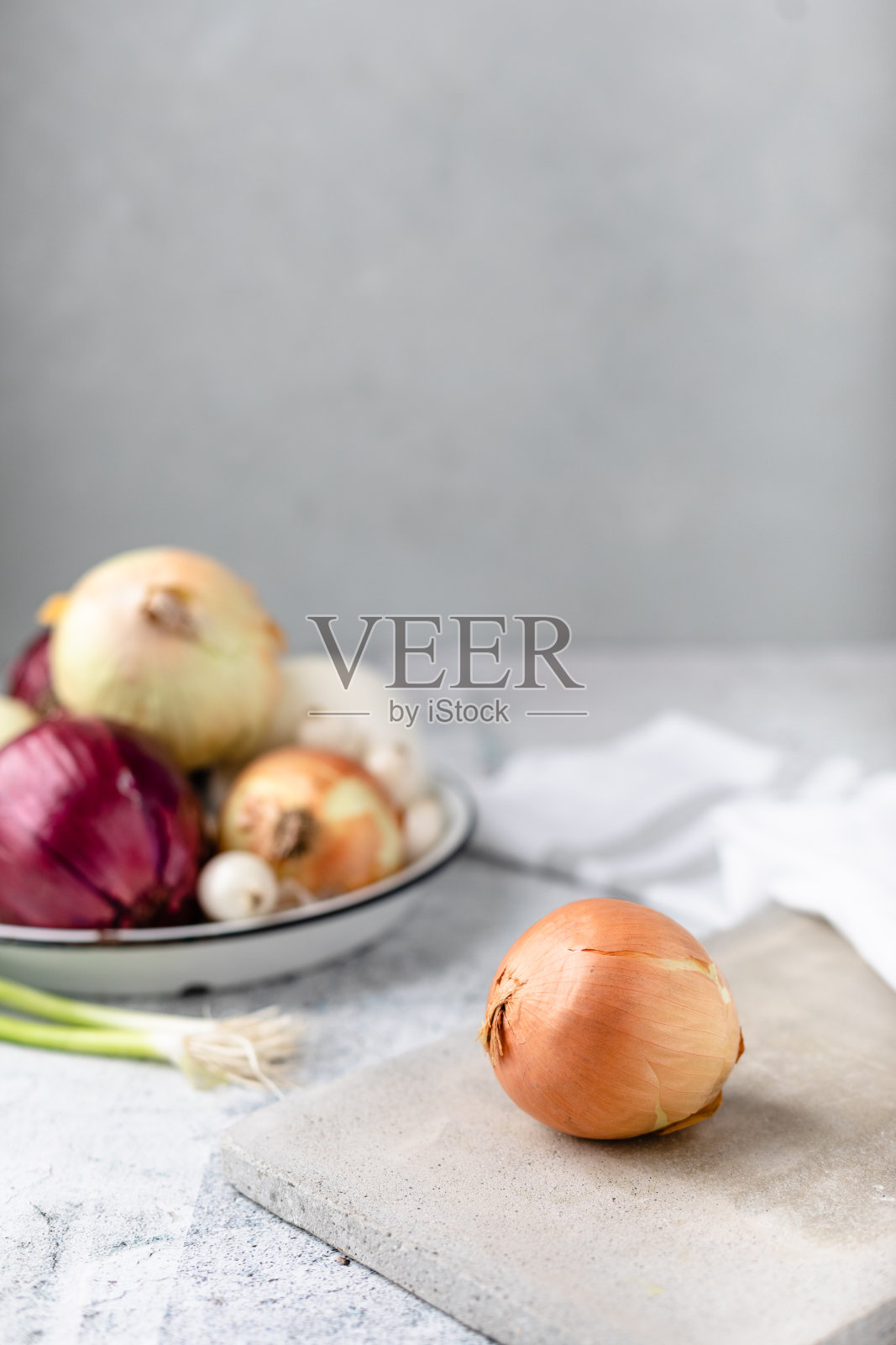 整个甜洋葱在水泥砧板上，几个品种的洋葱在背景中失去焦点照片摄影图片