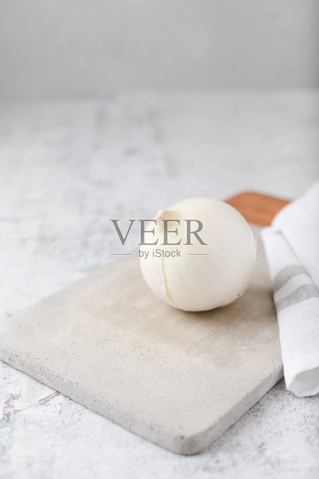 水泥台面上的水泥切菜板上的整颗白洋葱照片摄影图片