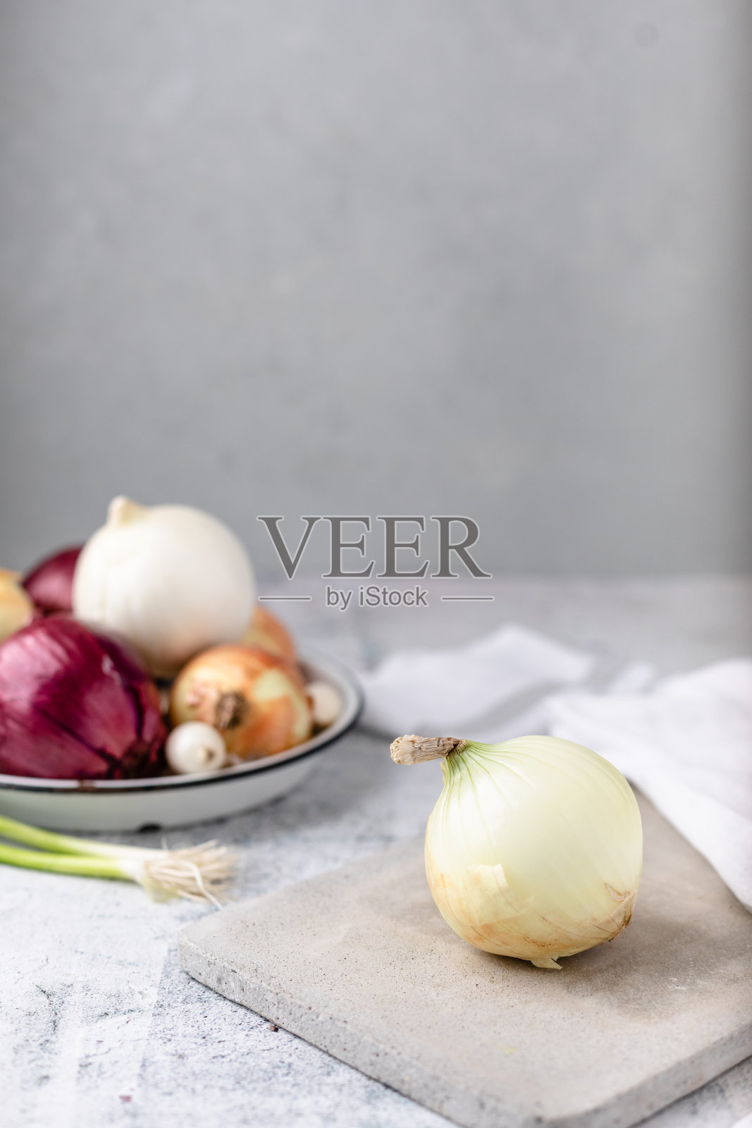 水泥切菜板上的整个黄洋葱，背景中有几个品种的洋葱失焦照片摄影图片