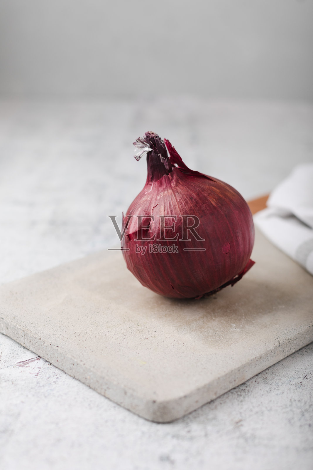 水泥台面上的水泥砧板上的整颗红洋葱照片摄影图片