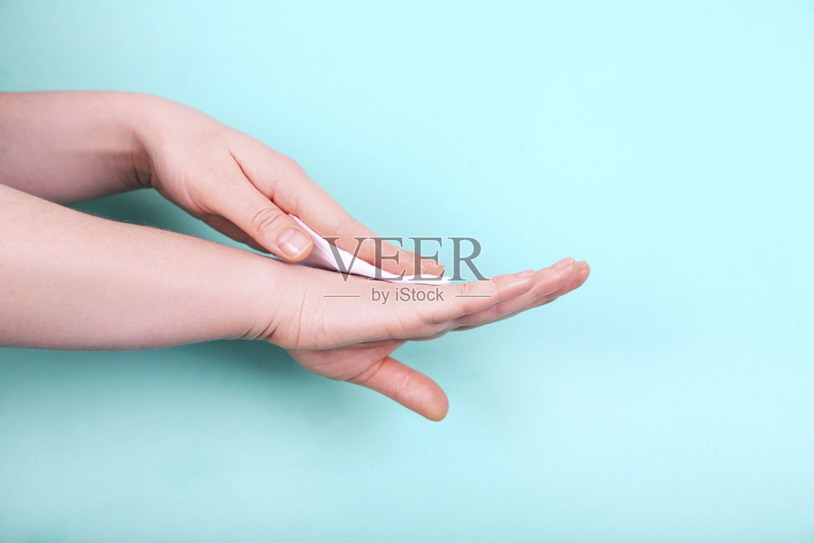 一个女人正在用白色的软纸巾擦手。照片摄影图片