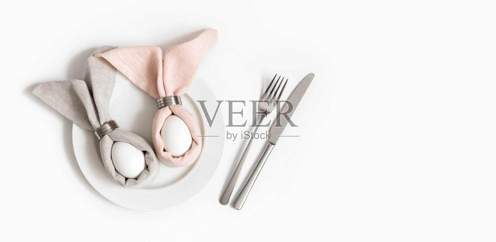 复活节概念彩蛋在复活节兔子餐巾上的白色背景。节日的餐桌布置。照片摄影图片