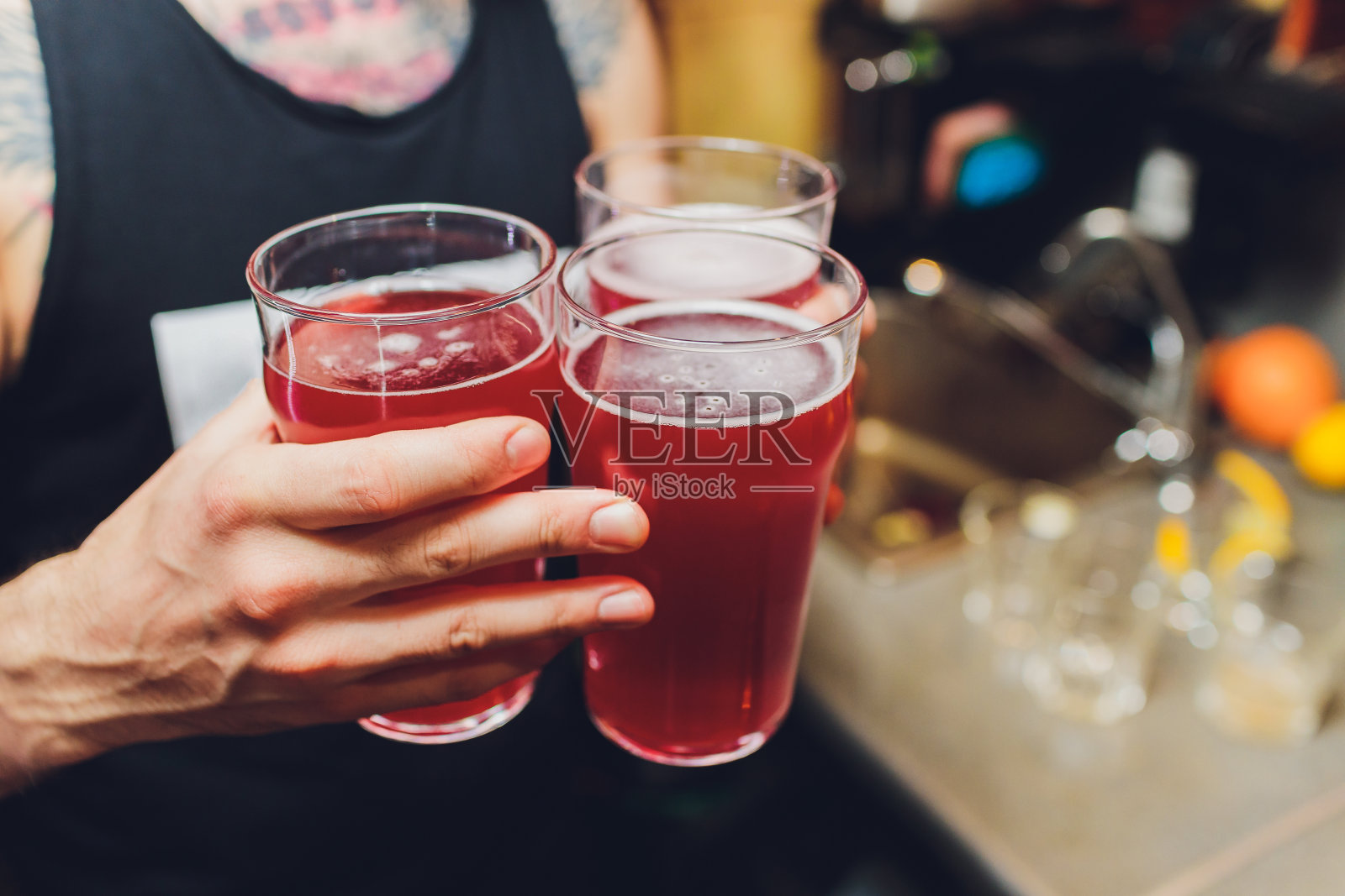 拿着三杯红啤酒的女人。照片摄影图片