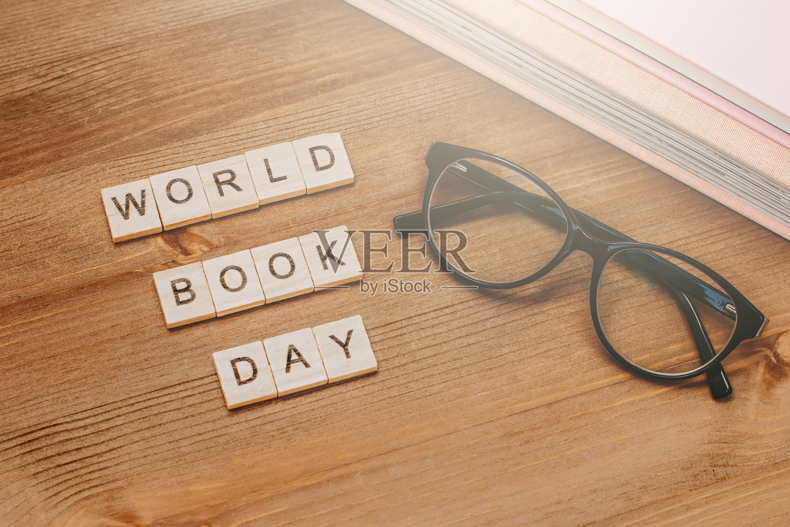单词世界读书日由带黑眼镜的木块和成堆的书组成。图书假期的背景照片摄影图片