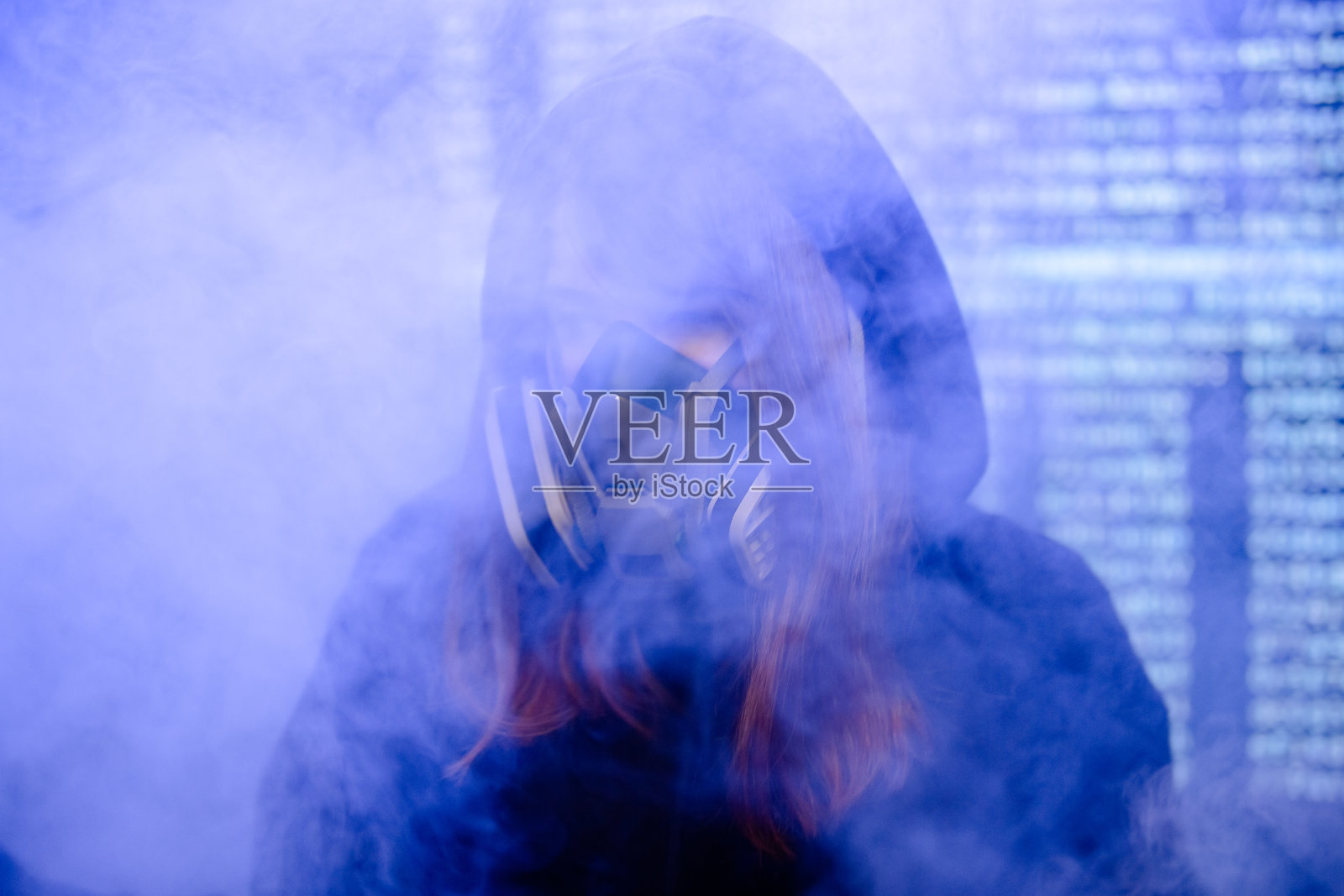 一个穿着黑色连帽衫戴着防毒面具的女孩在她面前的烟雾中照片摄影图片