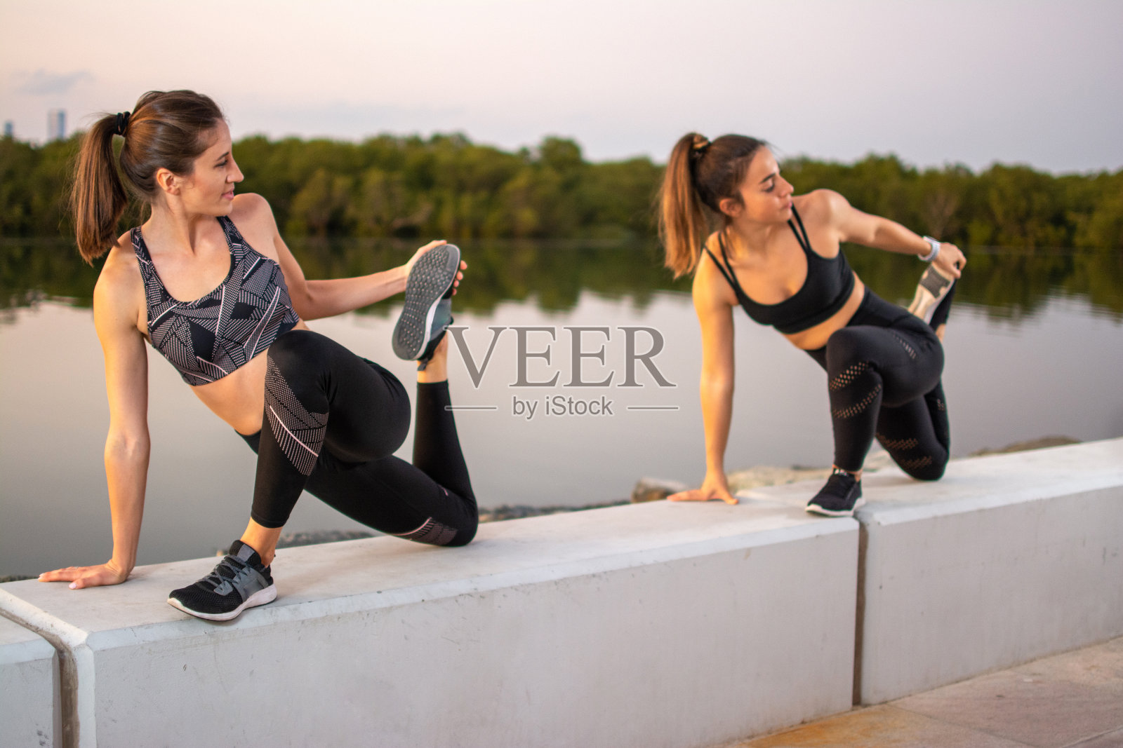 两名年轻运动女性在户外一起伸展身体照片摄影图片