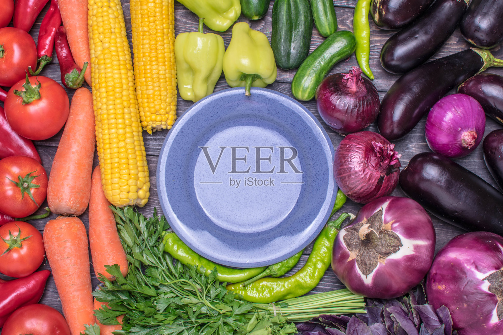 桌面上排列着各种新鲜的水果和蔬菜，按颜色分类——辣椒、番茄、玉米、胡萝卜、青菜沙拉、香菜、茄子、黄瓜、罗勒、莳萝、洋葱。健康食品的概念照片摄影图片