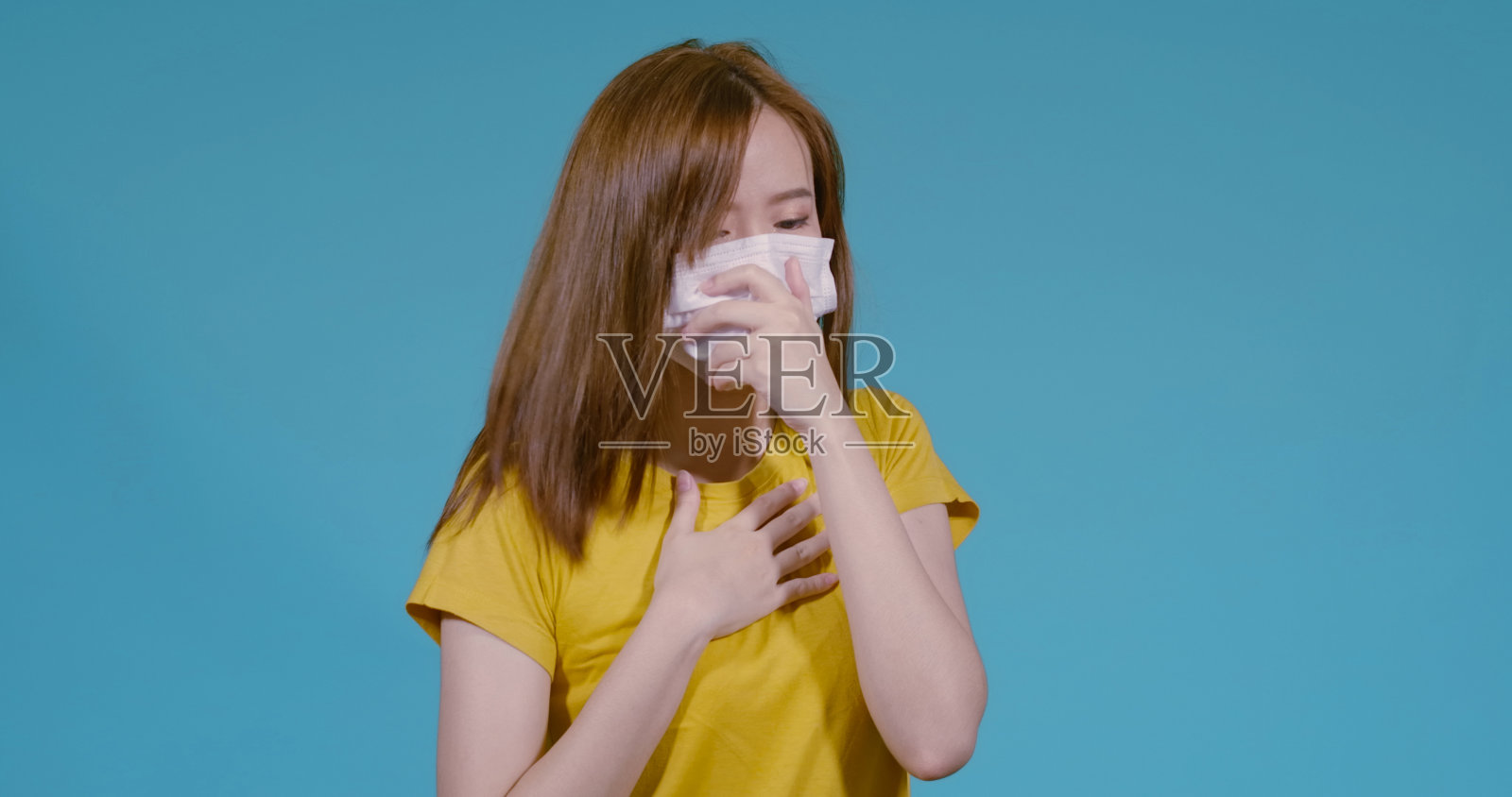 冠状病毒19口罩保护过滤的年轻亚洲妇女咳嗽感染她生病和感冒不健康的蓝色背景，疾病安全与口罩保护的概念照片摄影图片