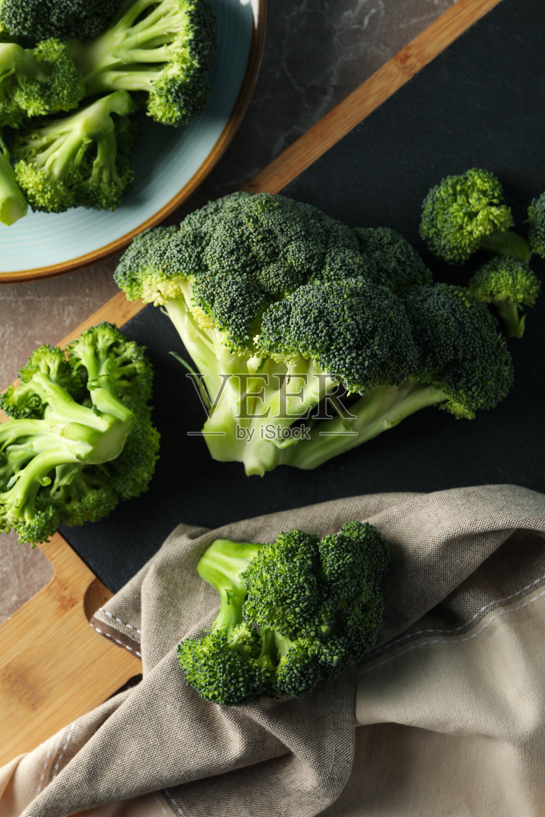 在灰色的桌子上，面板和盘子与西兰花，俯视图。健康的食物照片摄影图片