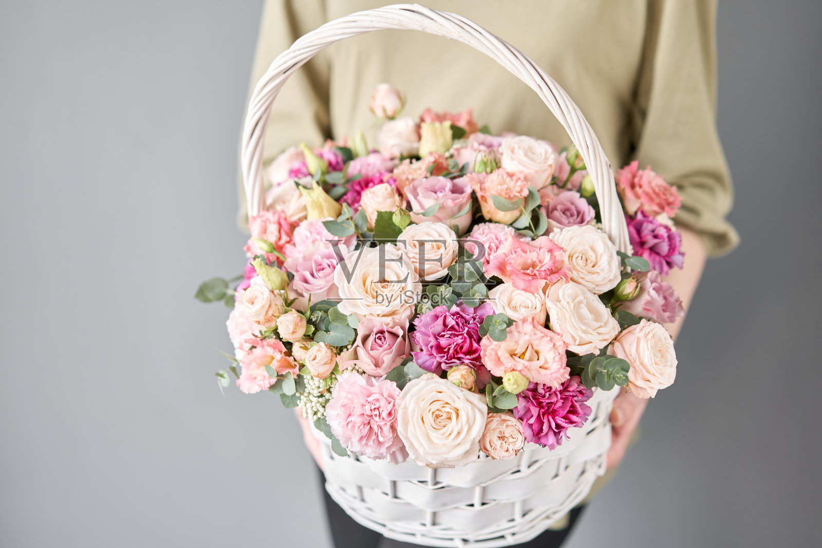 小花店及鲜花配送。柳条花篮插花。女人手里拿着一束美丽的混合鲜花。英俊的新鲜的花束。照片摄影图片