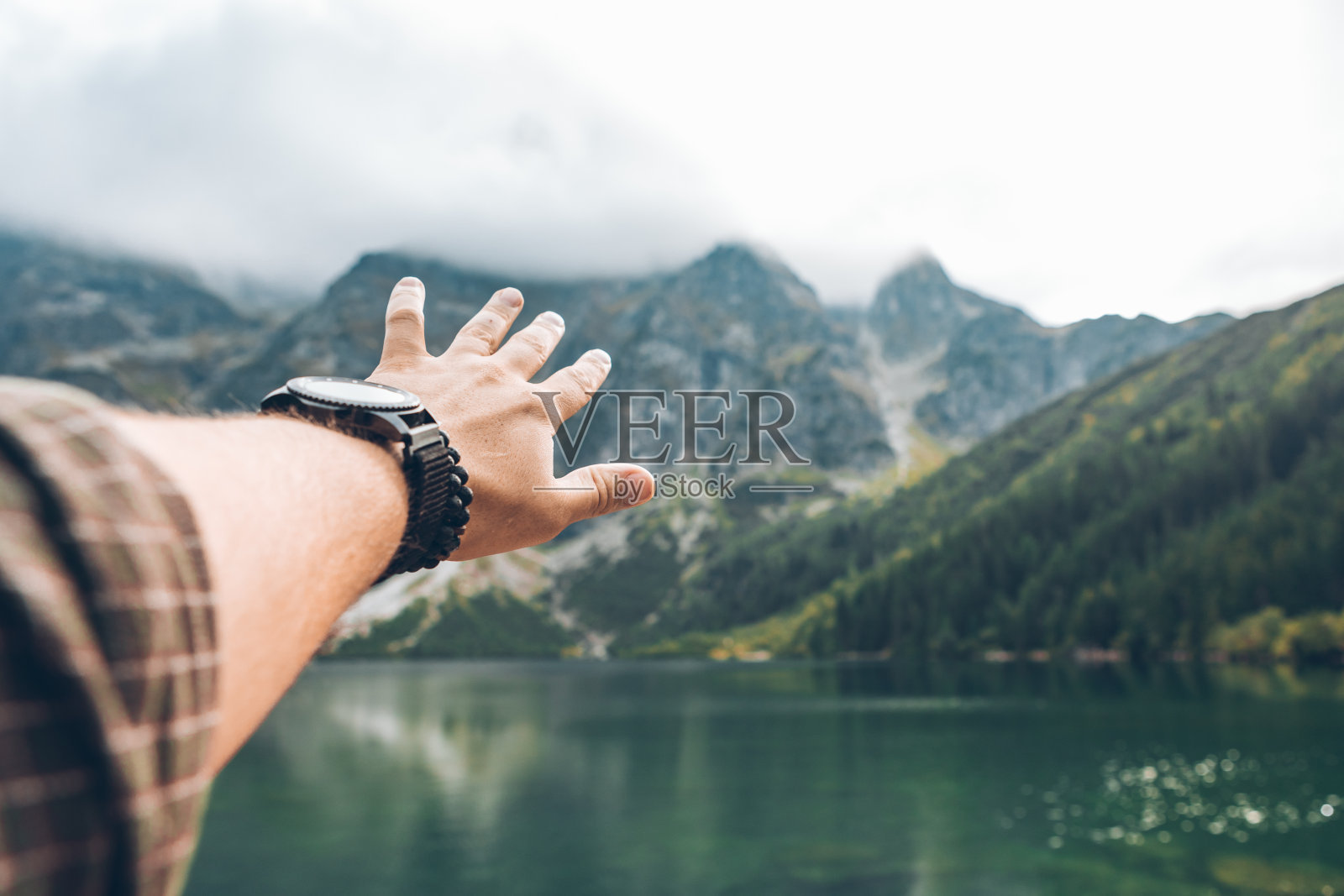 男人的手显示美丽的湖在山照片摄影图片