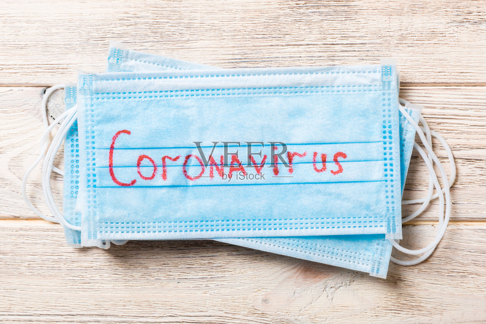 近距离观察在木质背景上印有冠状病毒字样的医用口罩。病毒。世界流行照片摄影图片