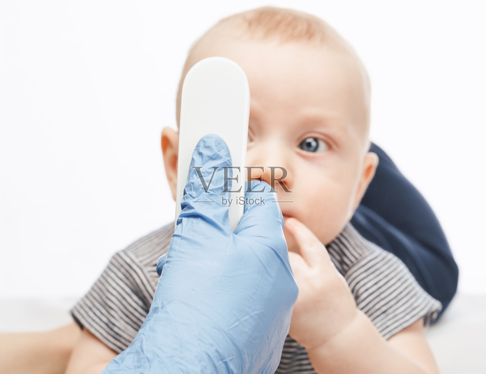 儿科医生用红外体温计检测男婴的体温照片摄影图片