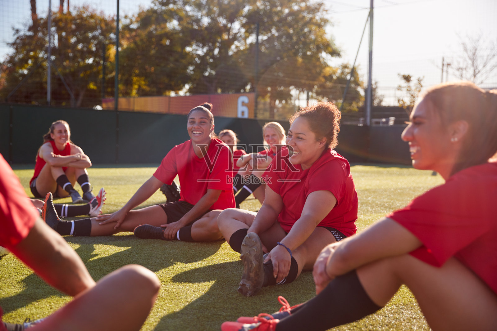女子足球队在户外草皮足球场进行足球比赛训练时伸展运动照片摄影图片