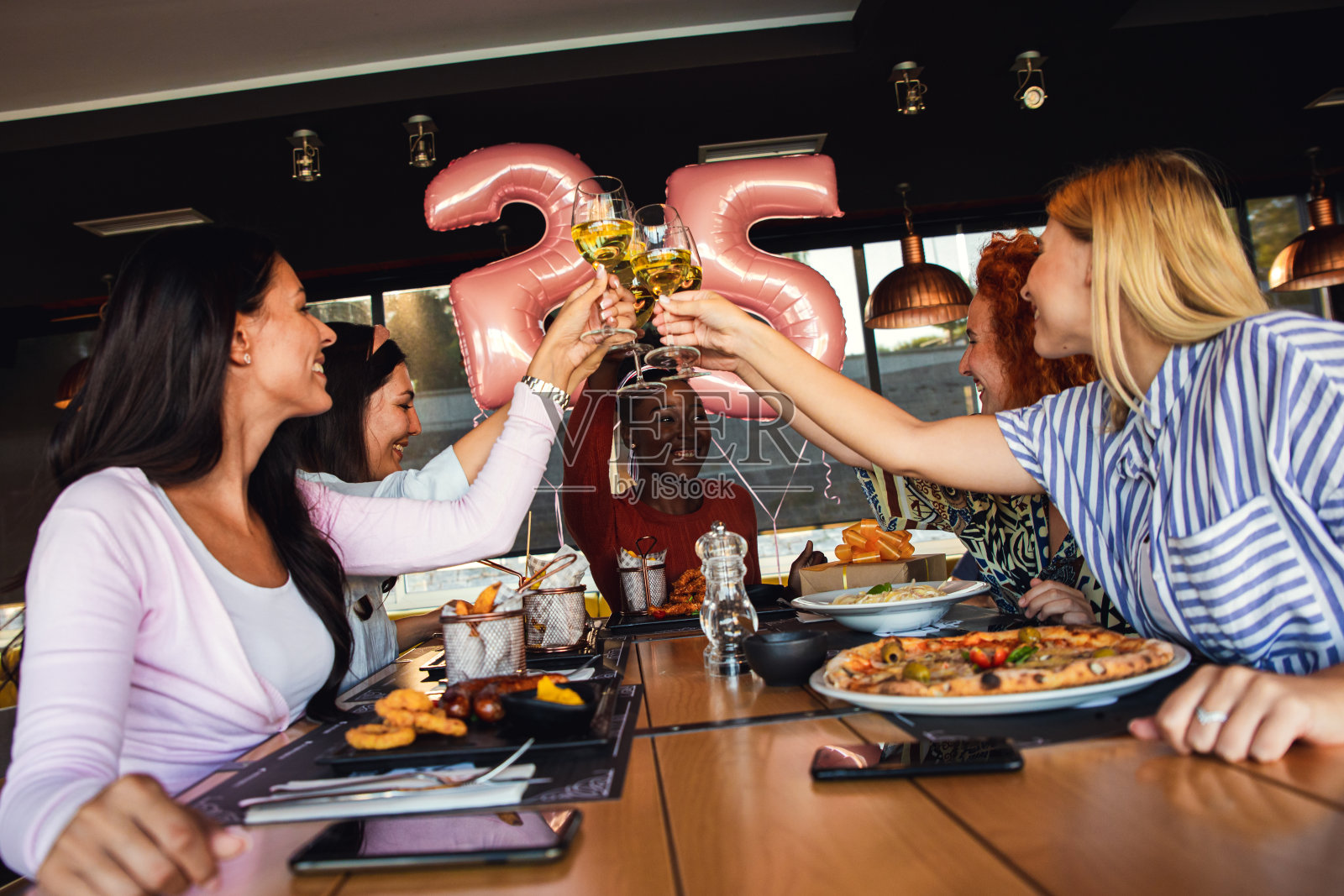 一群年轻的女性朋友在餐馆里玩乐，在餐桌上有说有笑。照片摄影图片