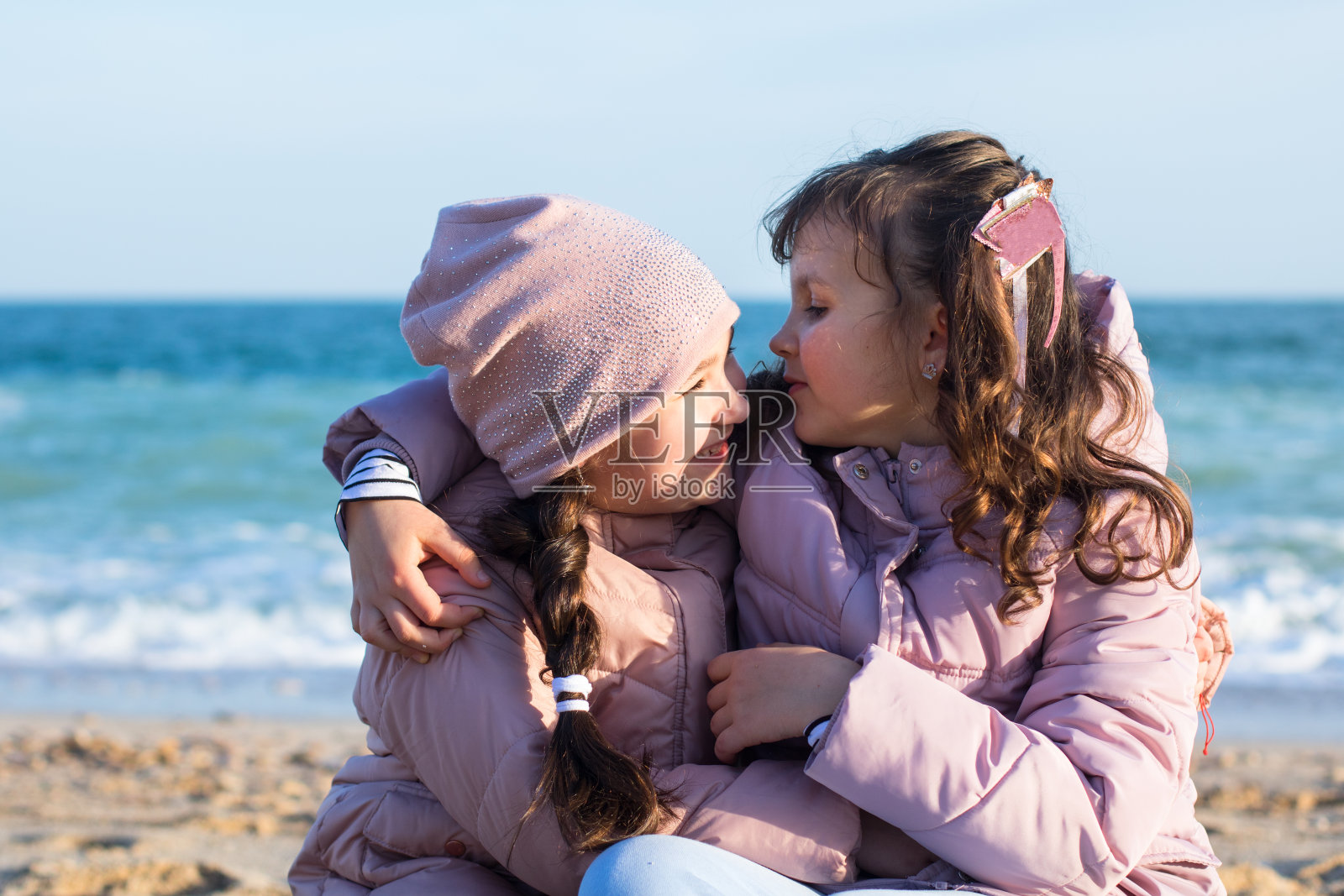 两个穿着夹克的白人小女孩在海滩上开心地在一起照片摄影图片
