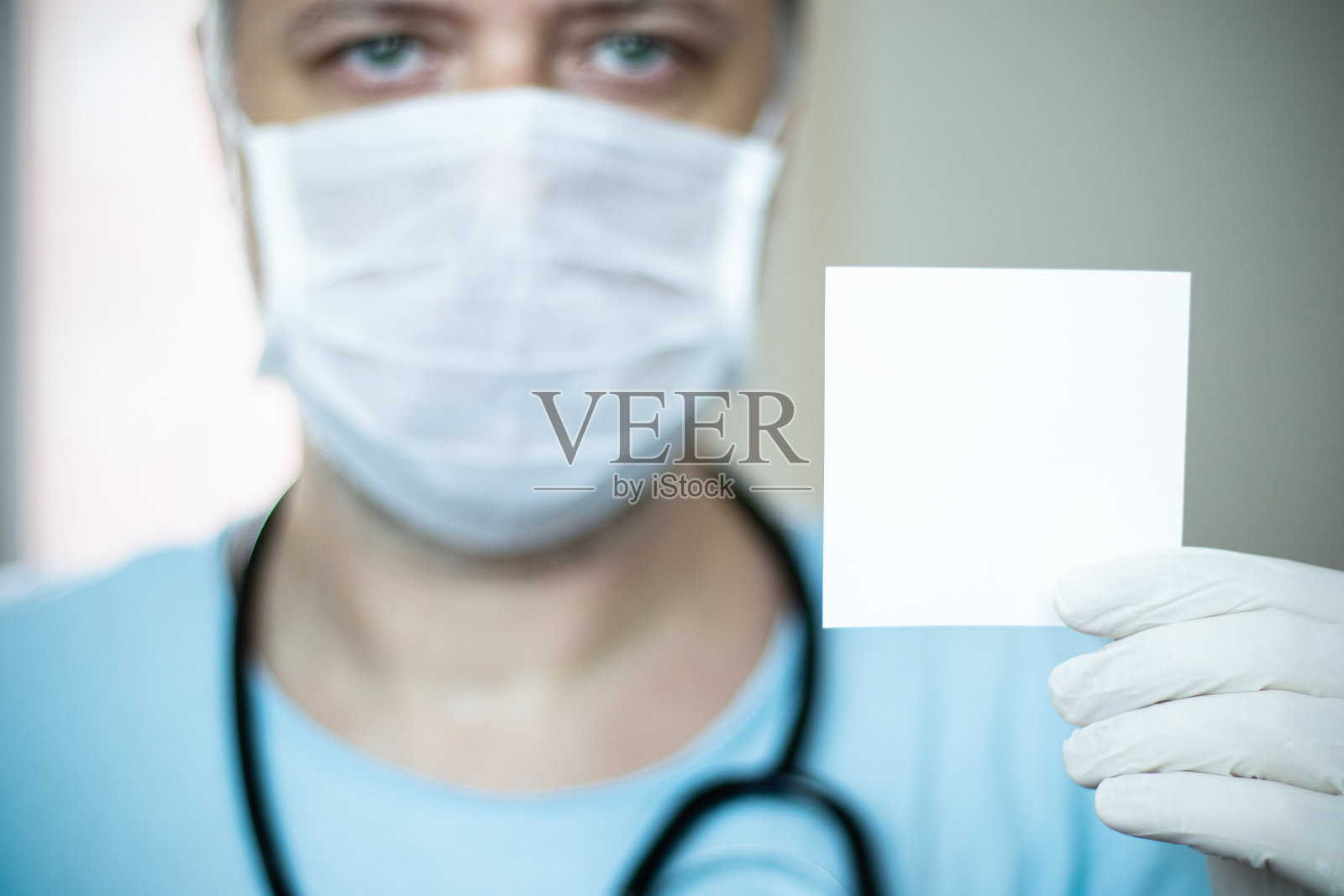 戴着口罩，拿着空白纸张的绿眼睛中年医生照片摄影图片