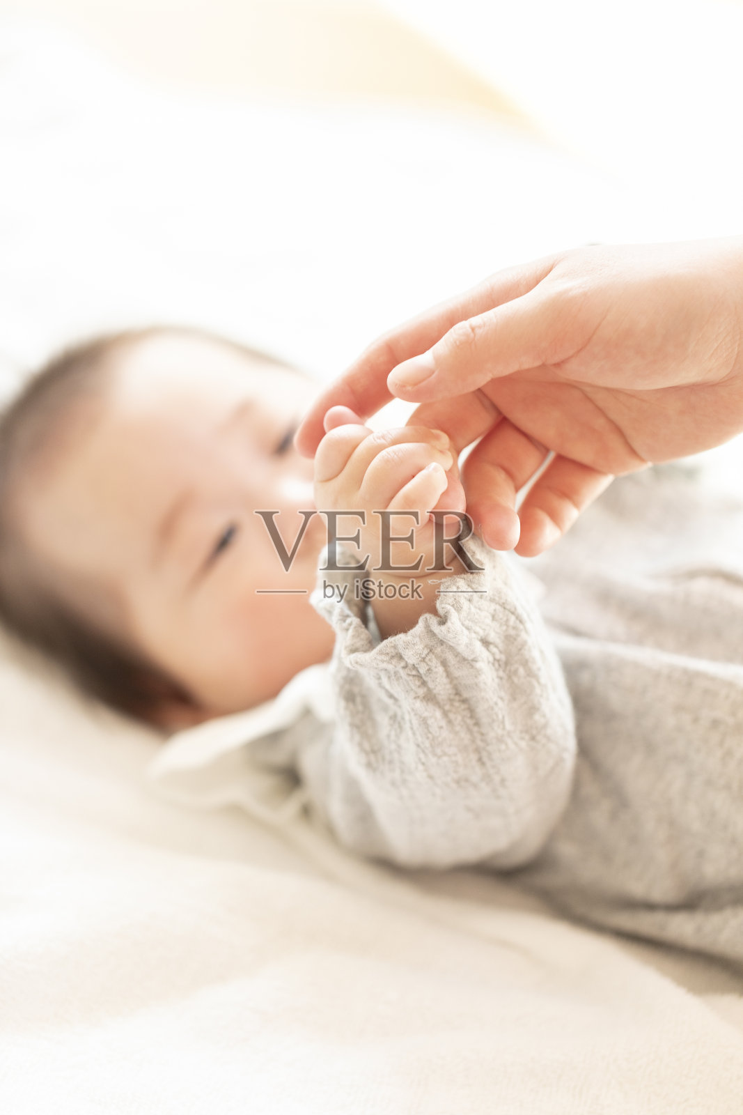 母亲手牵着婴儿的手在明亮的房间里照片摄影图片