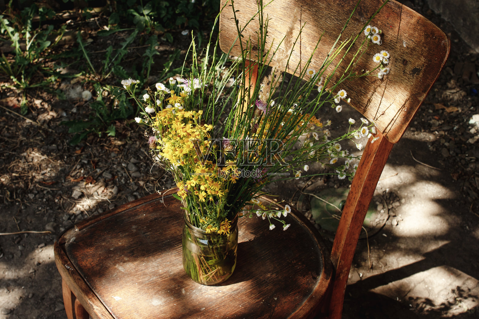 乡间别墅夏日里，旧木椅上放着一束乡村的野花照片摄影图片