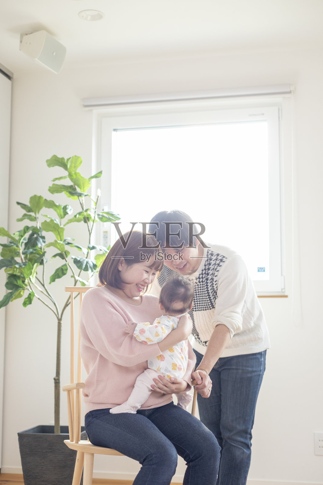 爸爸和妈妈抱着一个婴儿在一个明亮的房间里照片摄影图片