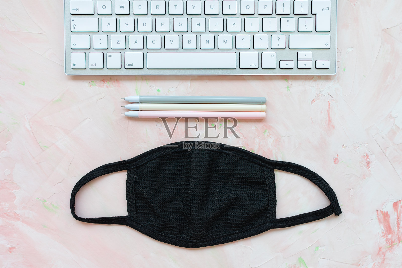 家庭办公室的背景。面具和键盘在粉红色照片摄影图片