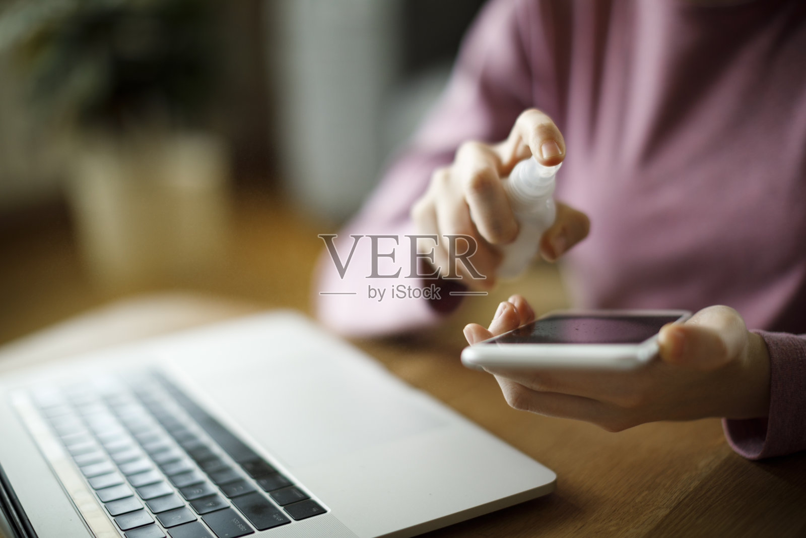 年轻女子用消毒剂喷雾清洁智能手机屏幕照片摄影图片