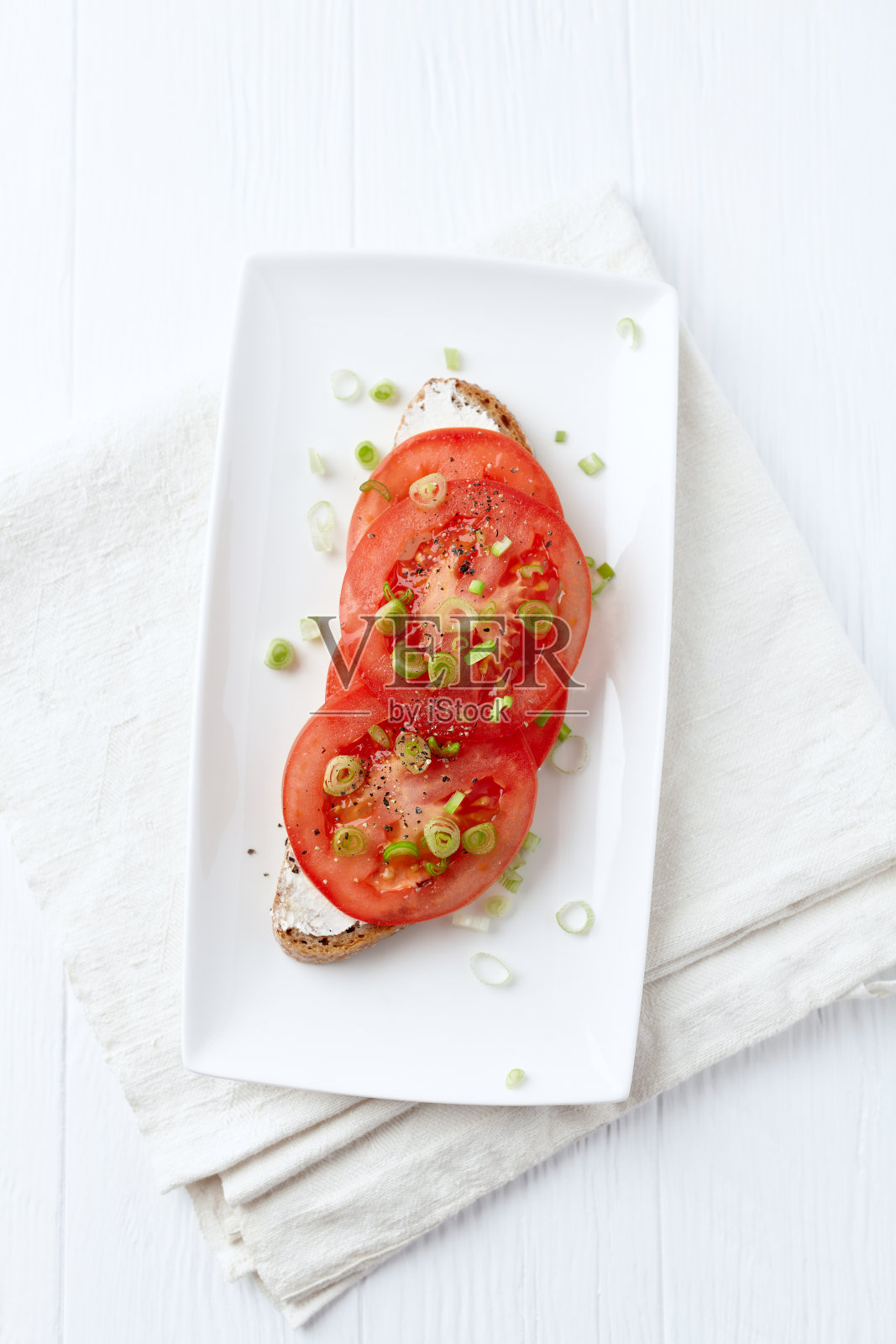 软奶酪和西红柿的三明治。明亮的木制背景。前视图。照片摄影图片