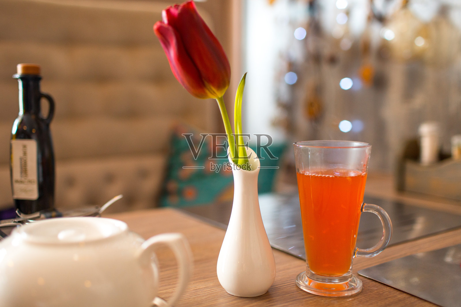 橙色茶饮料在一个透明的玻璃和郁金香花花瓶在桌子上照片摄影图片