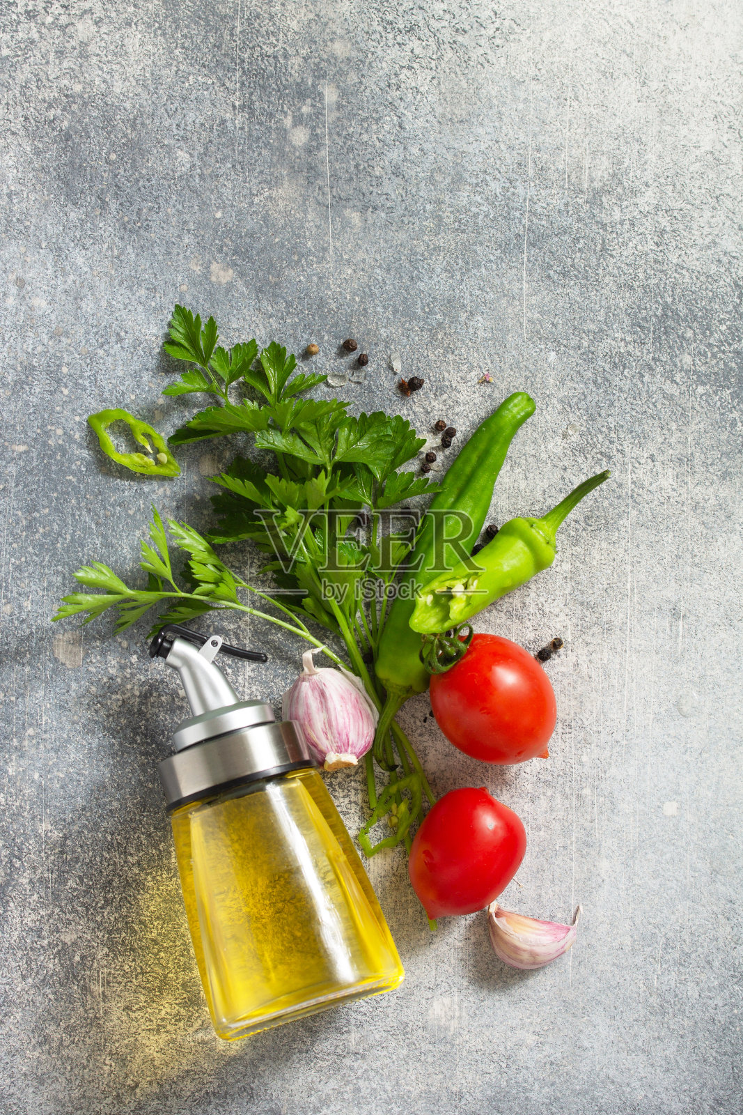 背景香料，香草和绿色蔬菜。石头桌上放着精选的香料、香草和橄榄油。俯视图平铺背景。照片摄影图片