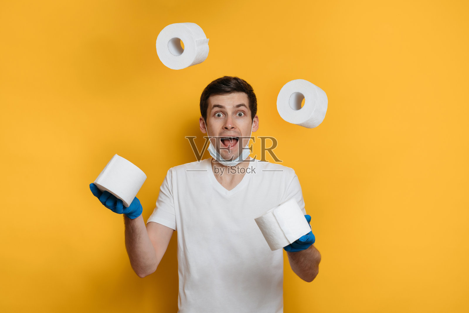 一个有趣的年轻人在黄色背景上玩弄一卷卫生纸照片摄影图片