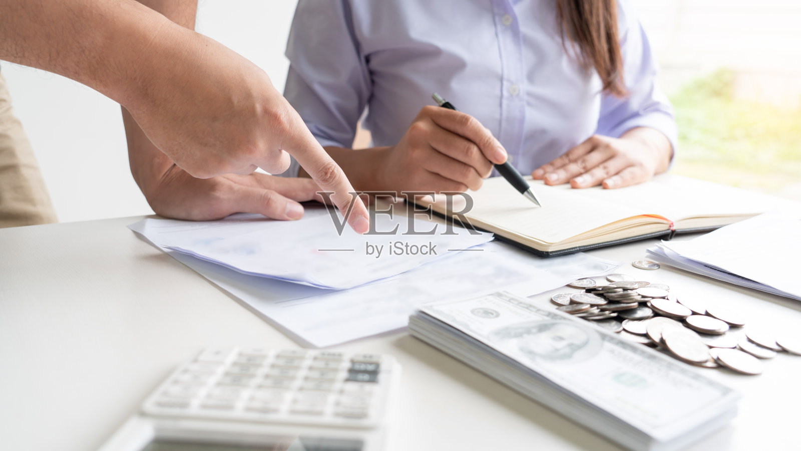 夫妇俩工作时用存折和计算器计算她每月的开支，计算财务数据，填写个人所得税申报表照片摄影图片