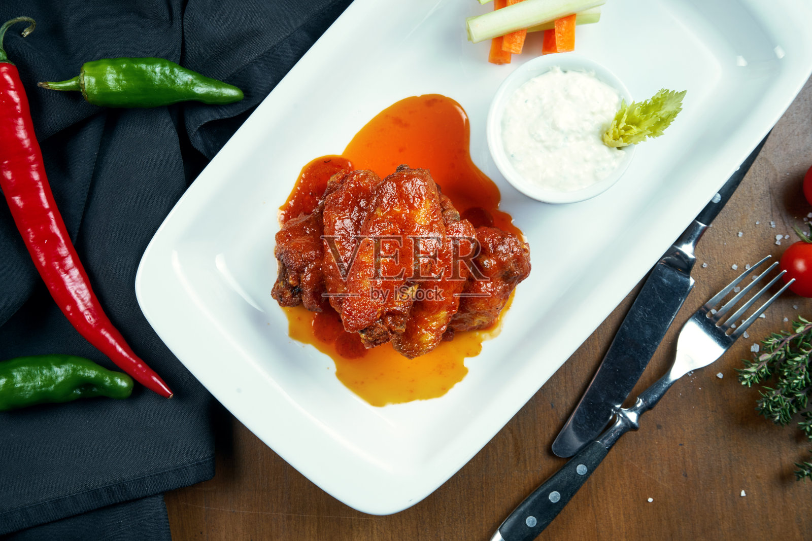 很棒的啤酒小吃-辣烤水牛鸡翅。烤鸡翅配沙拉，放在白色盘子里。关闭了。酒吧的食物照片摄影图片