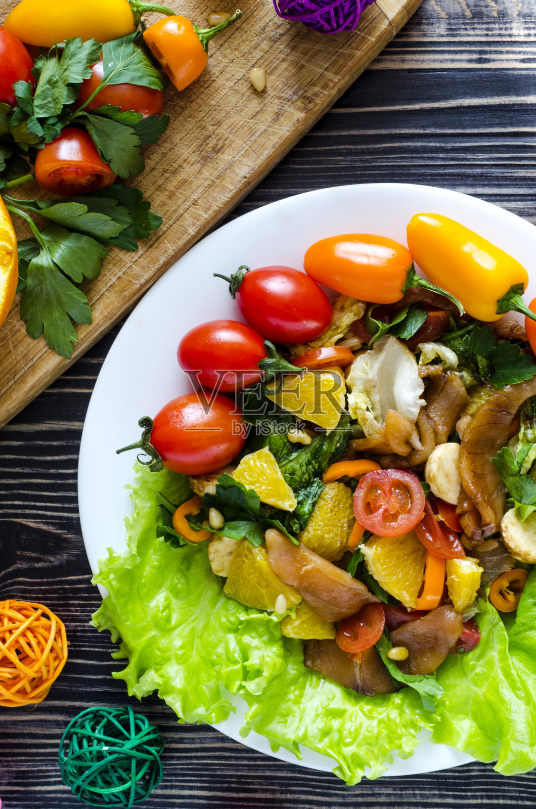 美味的春季沙拉，鱼和蔬菜放在一个白色的盘子里，用西红柿，香草和甜椒垂直装饰照片摄影图片
