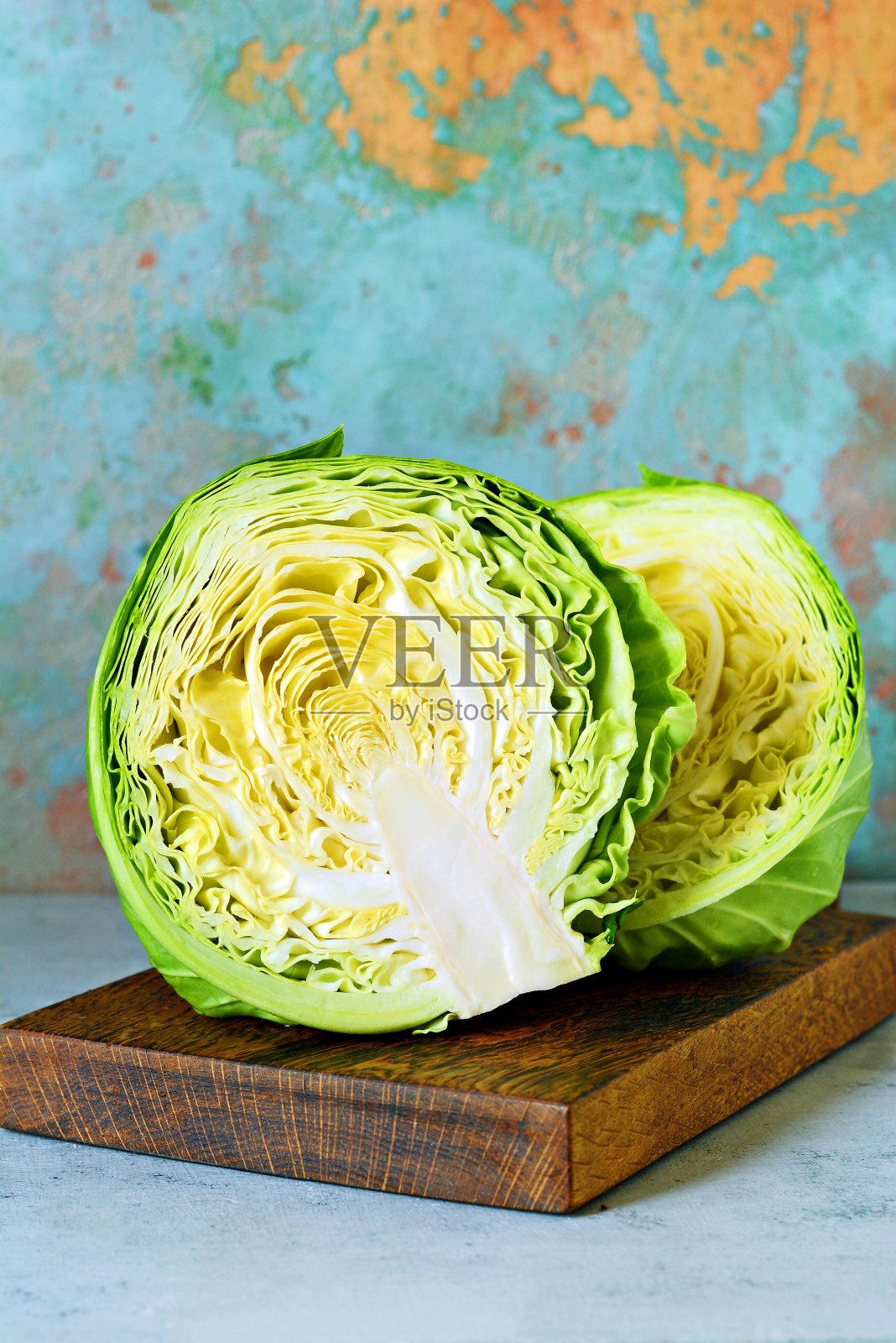 新鲜的卷心菜放在厨房的木板上，在蓝色的背景下切碎。切沙拉用的蔬菜。素食，饮食，维生素。照片摄影图片