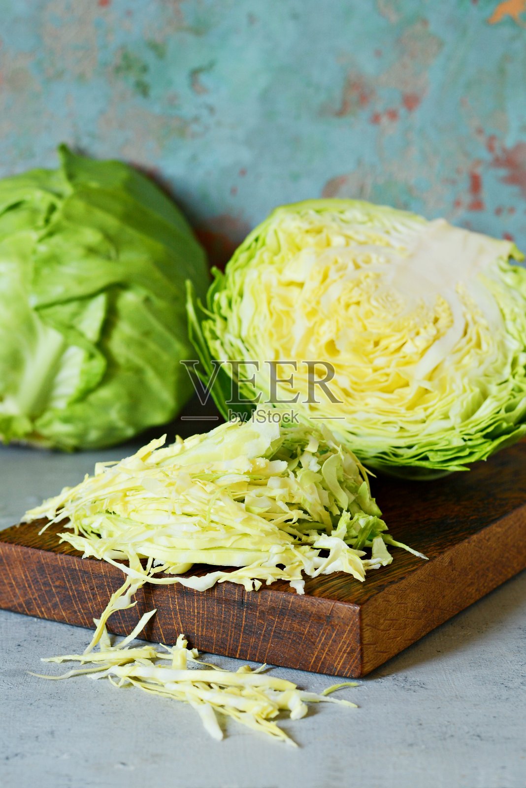 新鲜的卷心菜放在厨房的木板上，在蓝色的背景下切碎。切沙拉用的蔬菜。素食，饮食，维生素。照片摄影图片