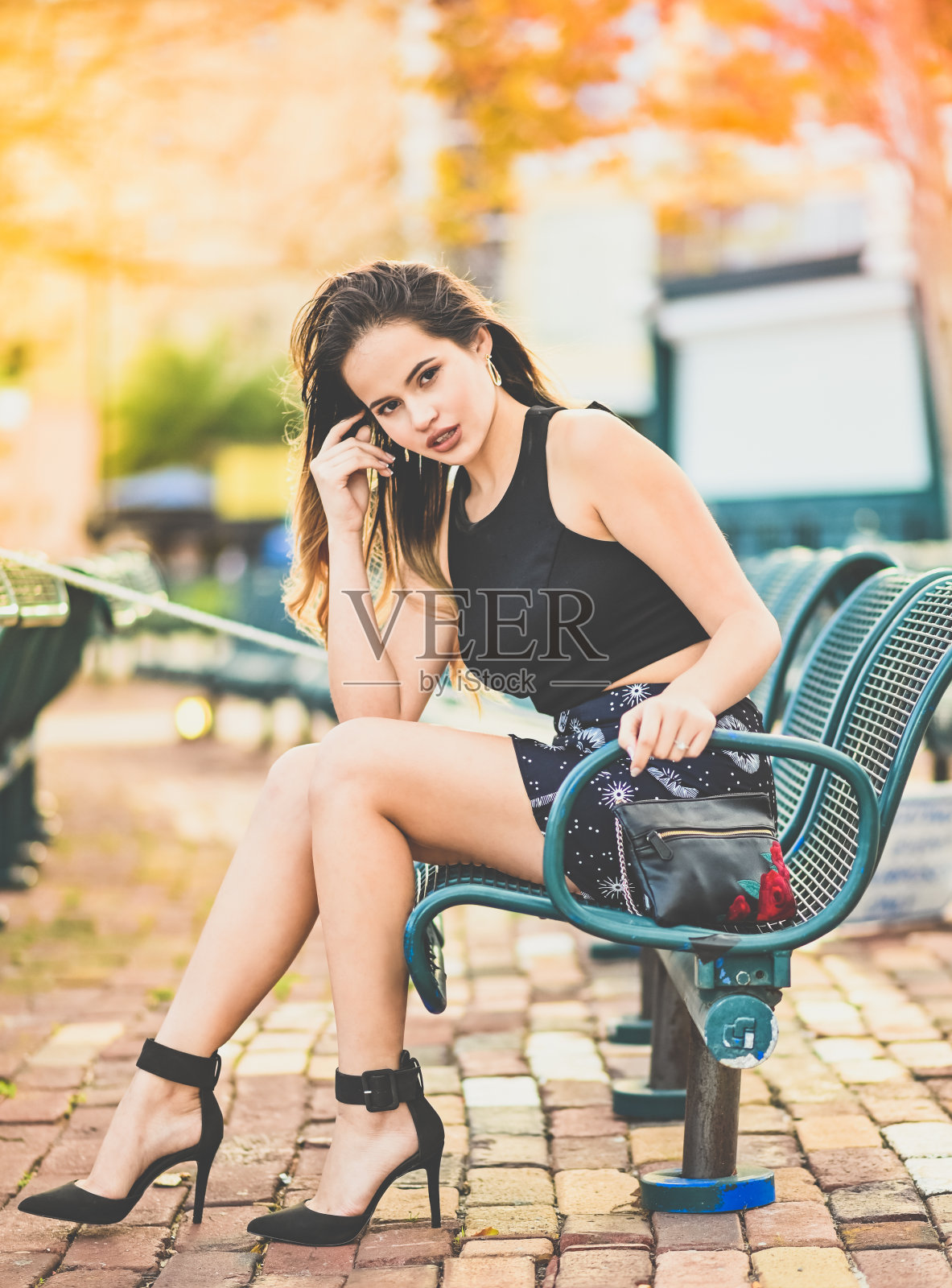 美丽年轻的拉丁模特在公园长凳摆姿势照片摄影图片