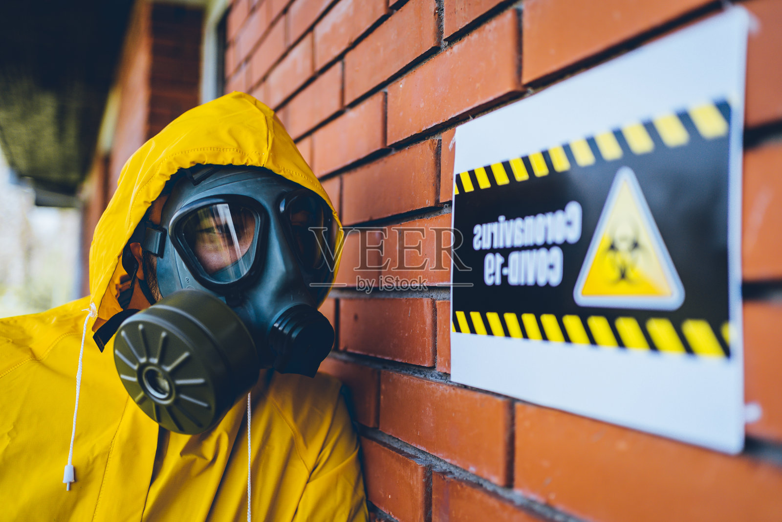 穿着防护服的人站在冠状病毒警告标志旁边照片摄影图片