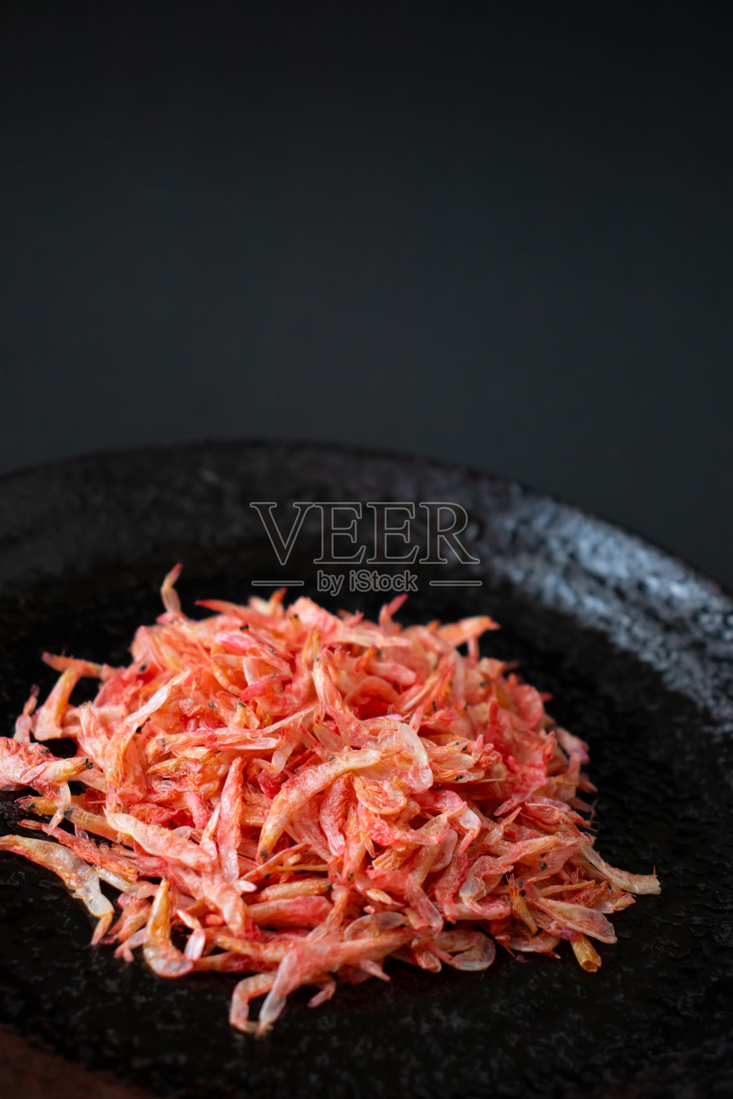 黑盘子里的虾米。照片摄影图片