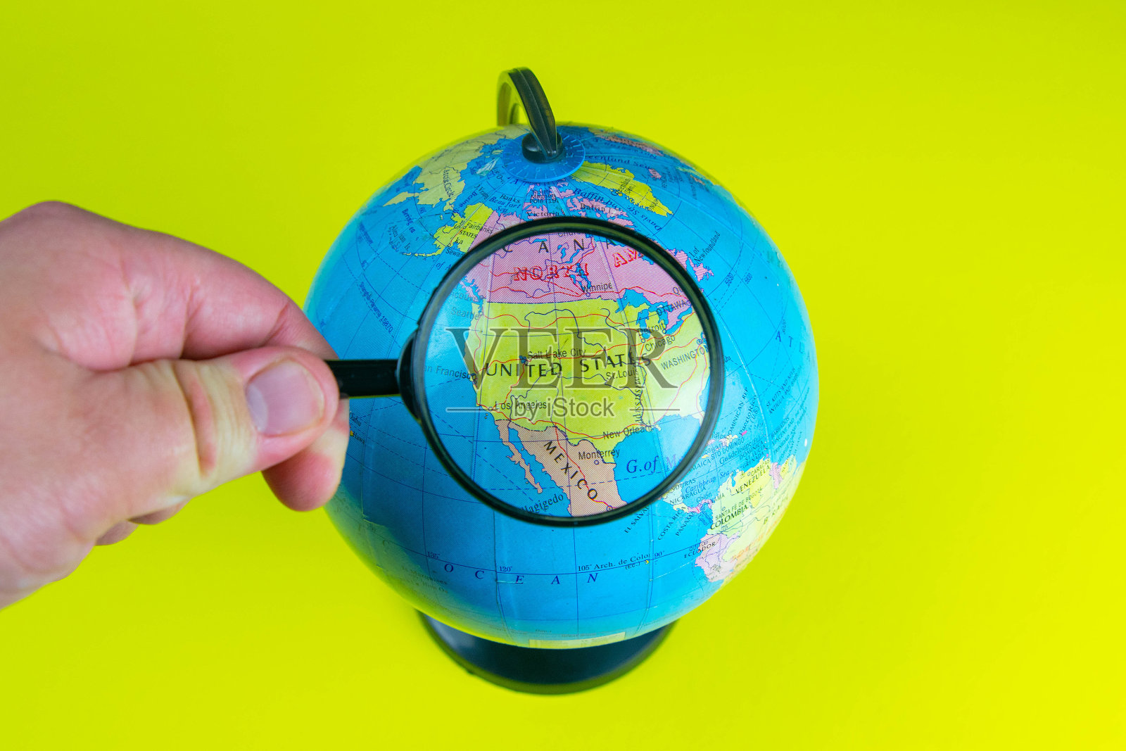 一只手拿着放大镜在近距离看全球图书馆，选择性聚焦美国照片摄影图片