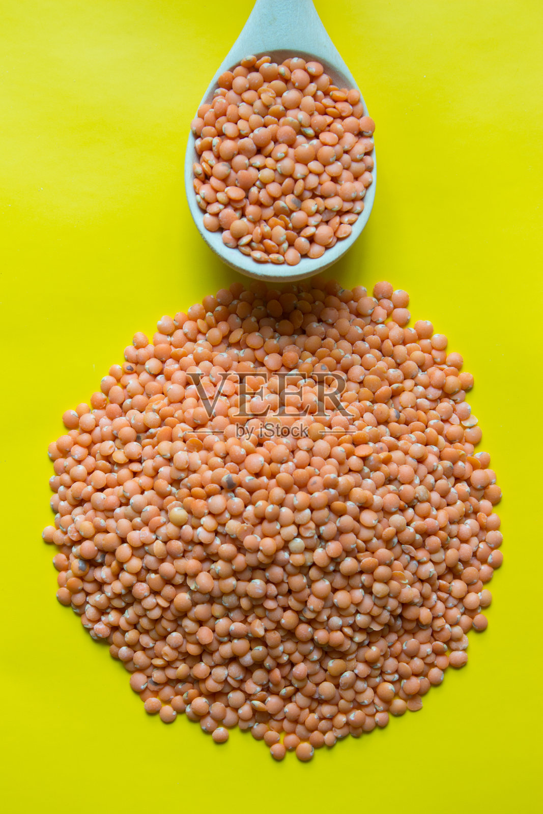 黄色背景的木勺里的有机红豆。前视图。照片摄影图片