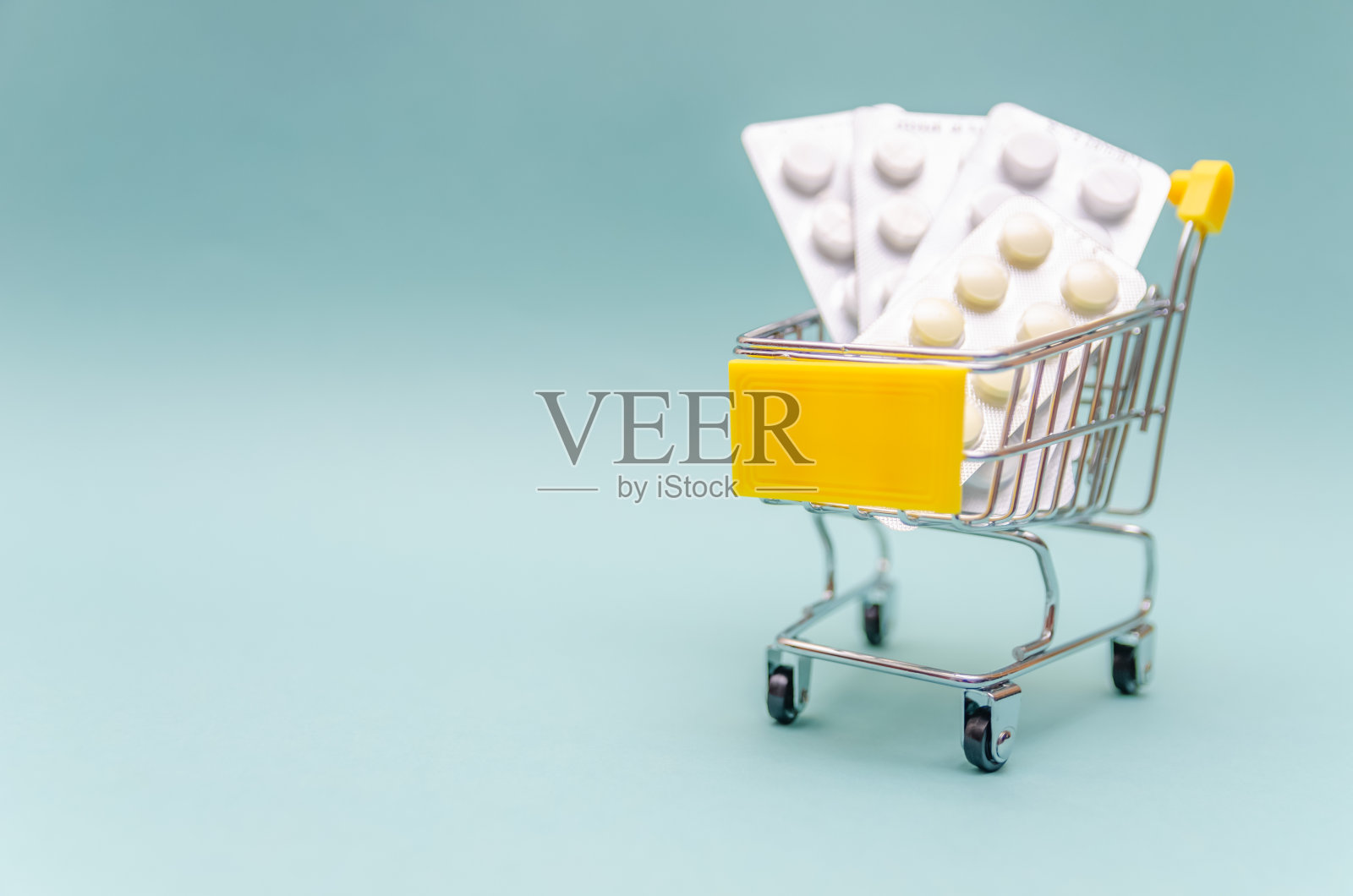 蓝色背景上的药丸购物车。网上购物的药品概念。文本复制空间照片摄影图片