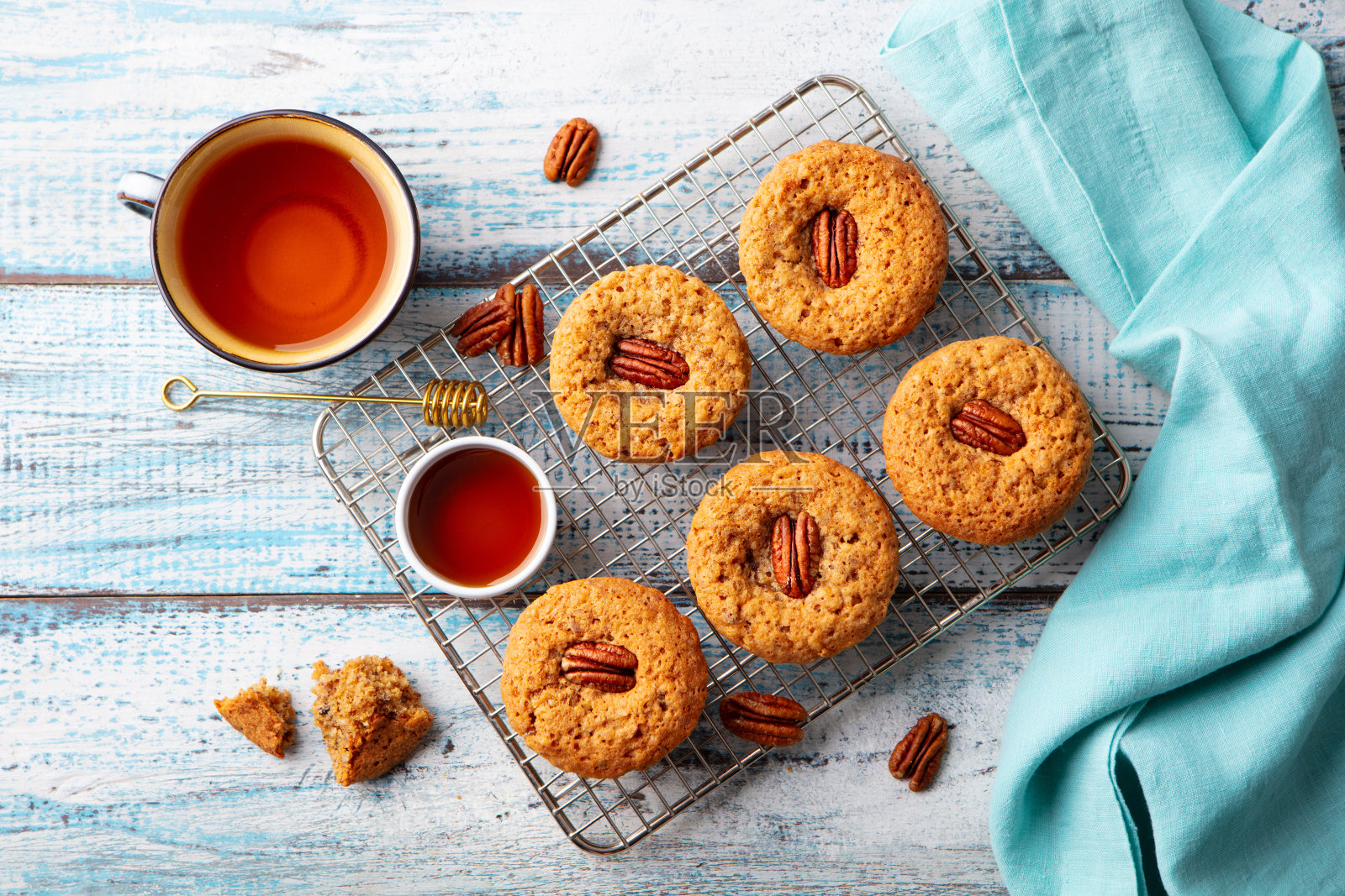 冷却架上的山核桃松饼配一杯茶。蓝色的木制背景。前视图。照片摄影图片