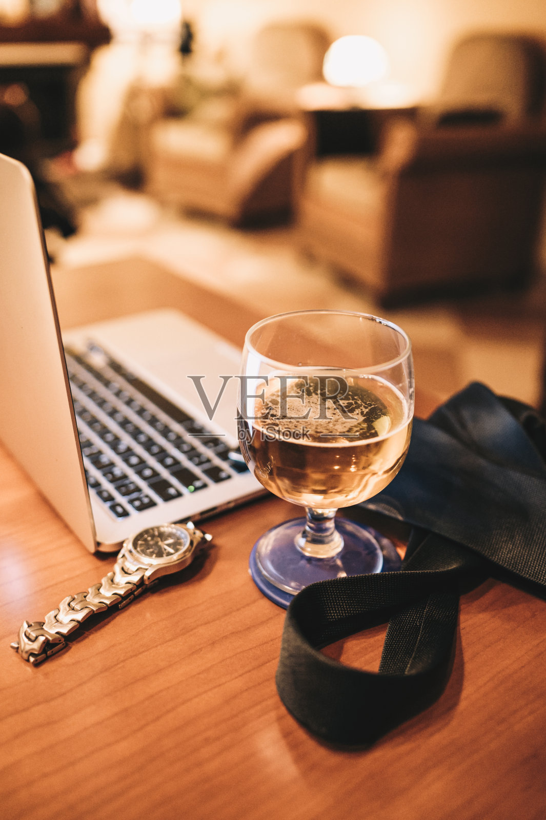 木桌上有一台笔记本电脑，一只手表，一条领带和一杯啤酒照片摄影图片