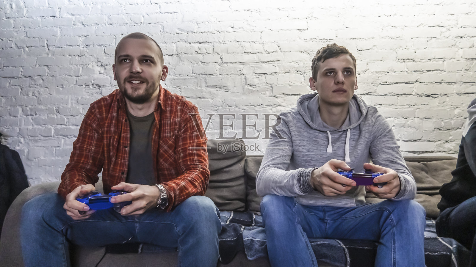 两个男人在白色砖墙前玩电子游戏照片摄影图片