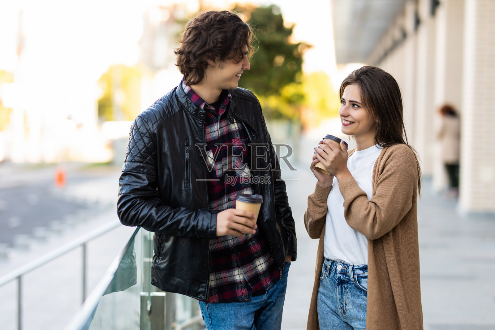 微笑情侣秋装打扮手持咖啡在街上对视散步照片摄影图片