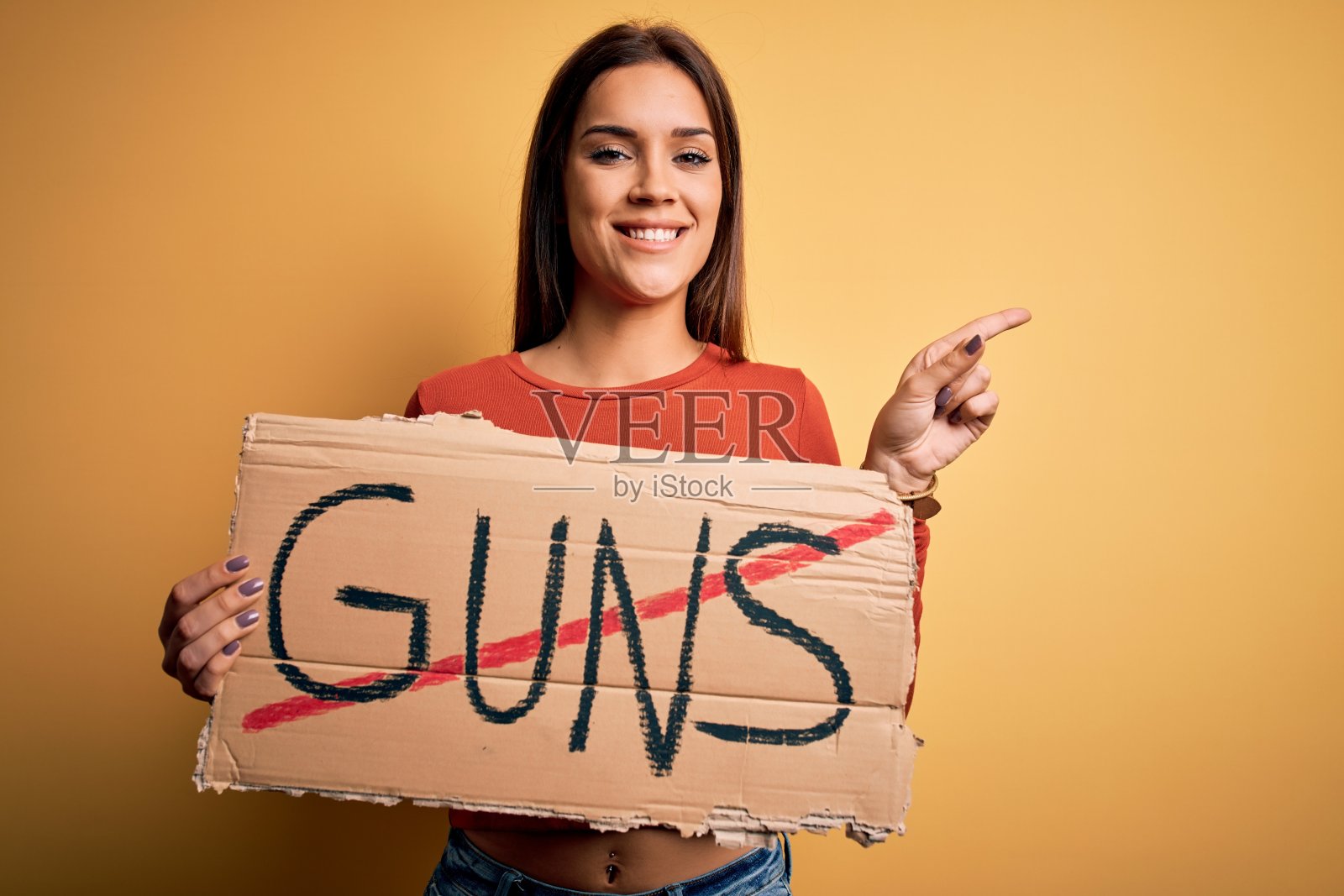 年轻美丽的激进女性要求和平，举着旗帜和枪支信息，非常高兴地用手和手指指向一边照片摄影图片