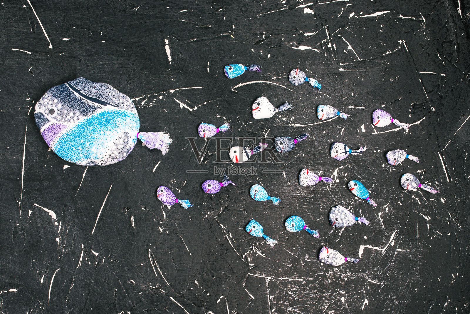 织物上的一群鱼跟着黑板上的领头鱼。领导、成功和团队合作的理念。商业理念中的领导力。照片摄影图片