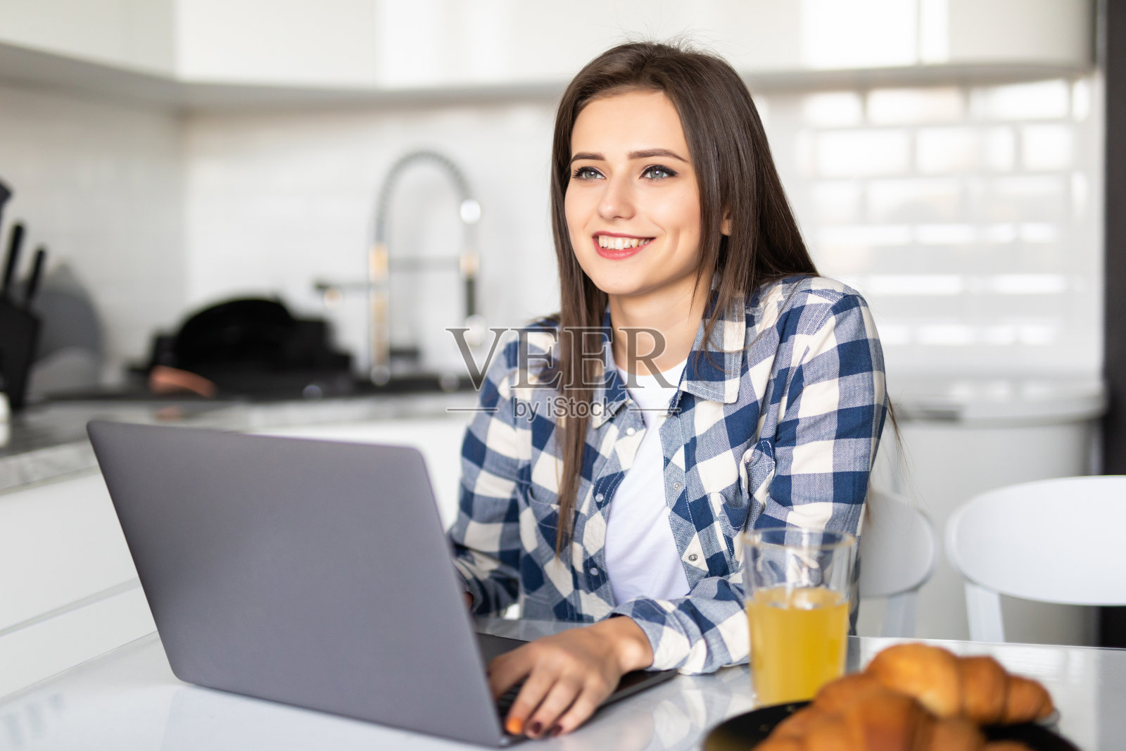 在家吃早餐时，在厨房里使用笔记本电脑的漂亮女人肖像照片摄影图片